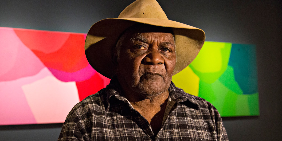 Pepai Jangala Carroll, from Ernabella Arts, in front of his work at the Tarnanthi Festival. Photo courtesy Art Gallery of SA. 