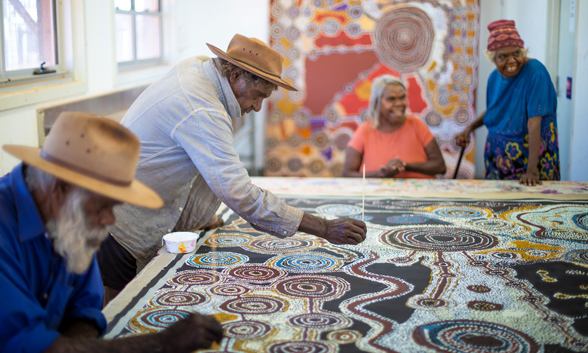 Taylor Cooper and Witjiti George working on a collaborative painting under the watchful eye of Matjangka Norris and Tjangali George; courtesy the artists and Kaltjiti Arts. Photo: Meg Hansen 