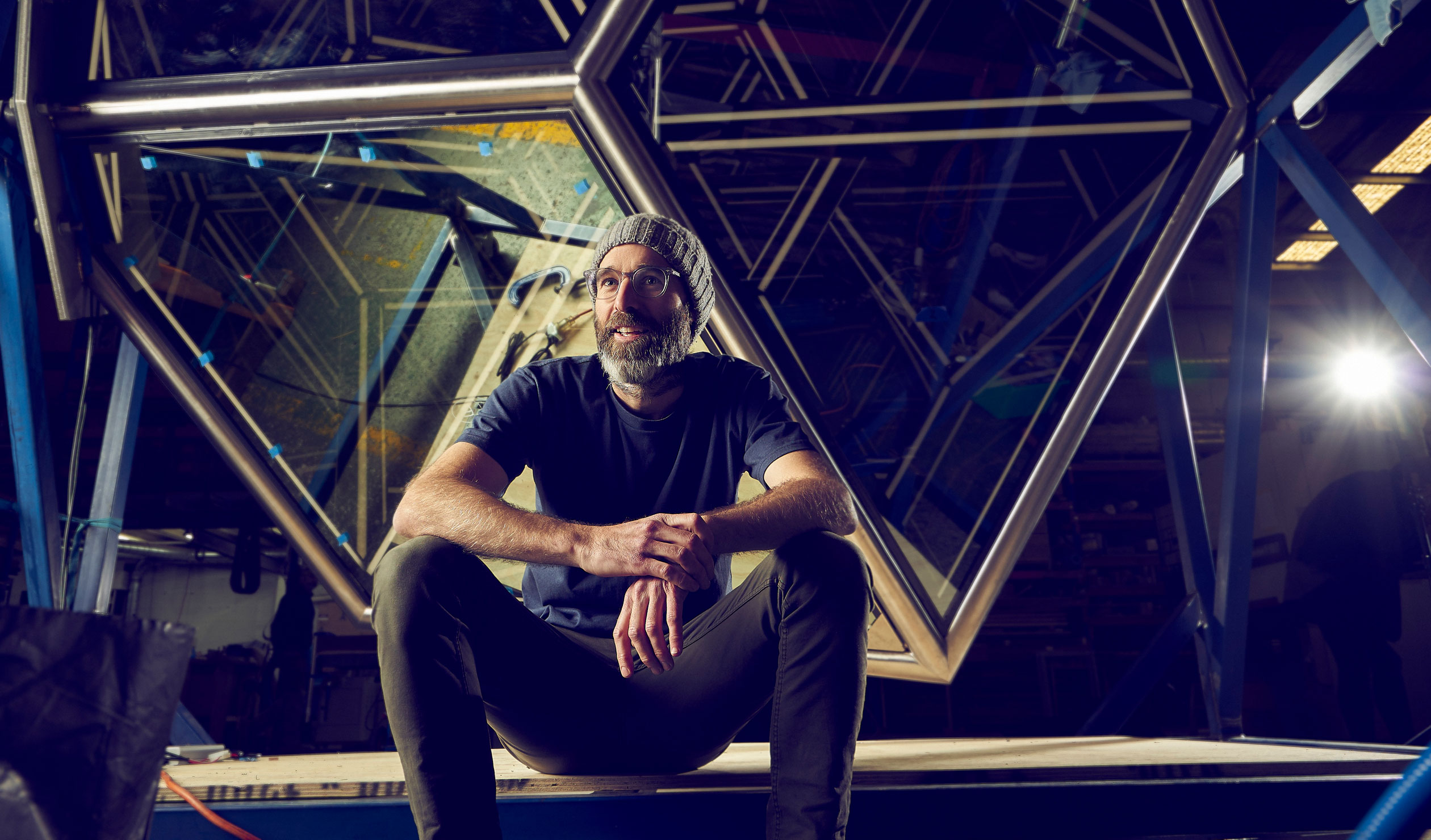 Jason Sims with his latest public artwork 'Golden Rhombohedron (Obtuse)' during its assembly at Gray Hawk Design. Photo: Aubrey Jonsson  
