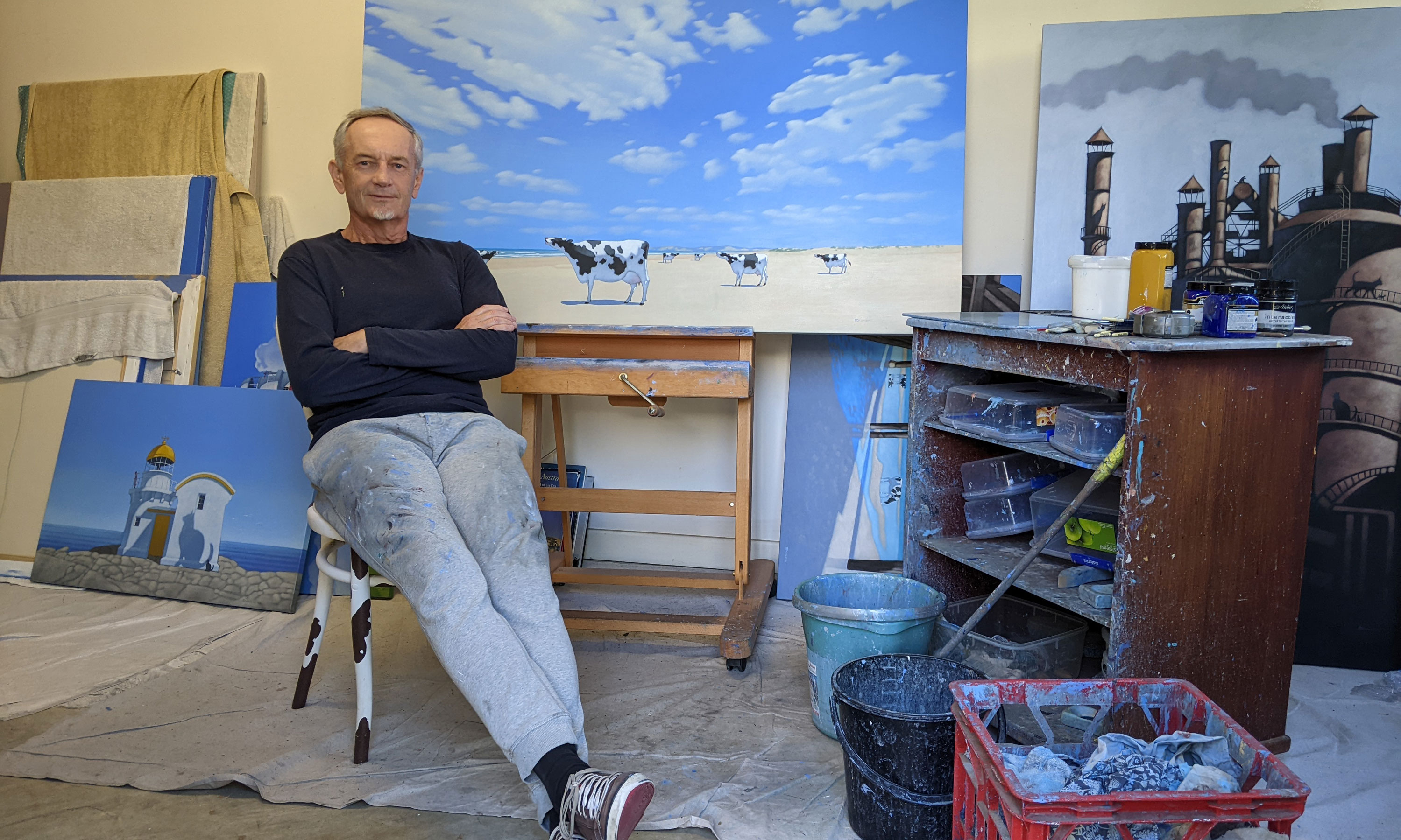 Andrew Baines in his Grange studio, with one of his famous paintings of cows on the beach sitting on the easel behind him. Photo: Carolyn Wade