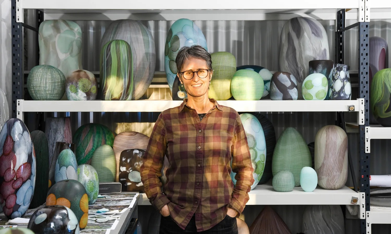 Glass artist Clare Belfrage surrounded by some of the works in her studio. Photo: Jack Fenby / InReview