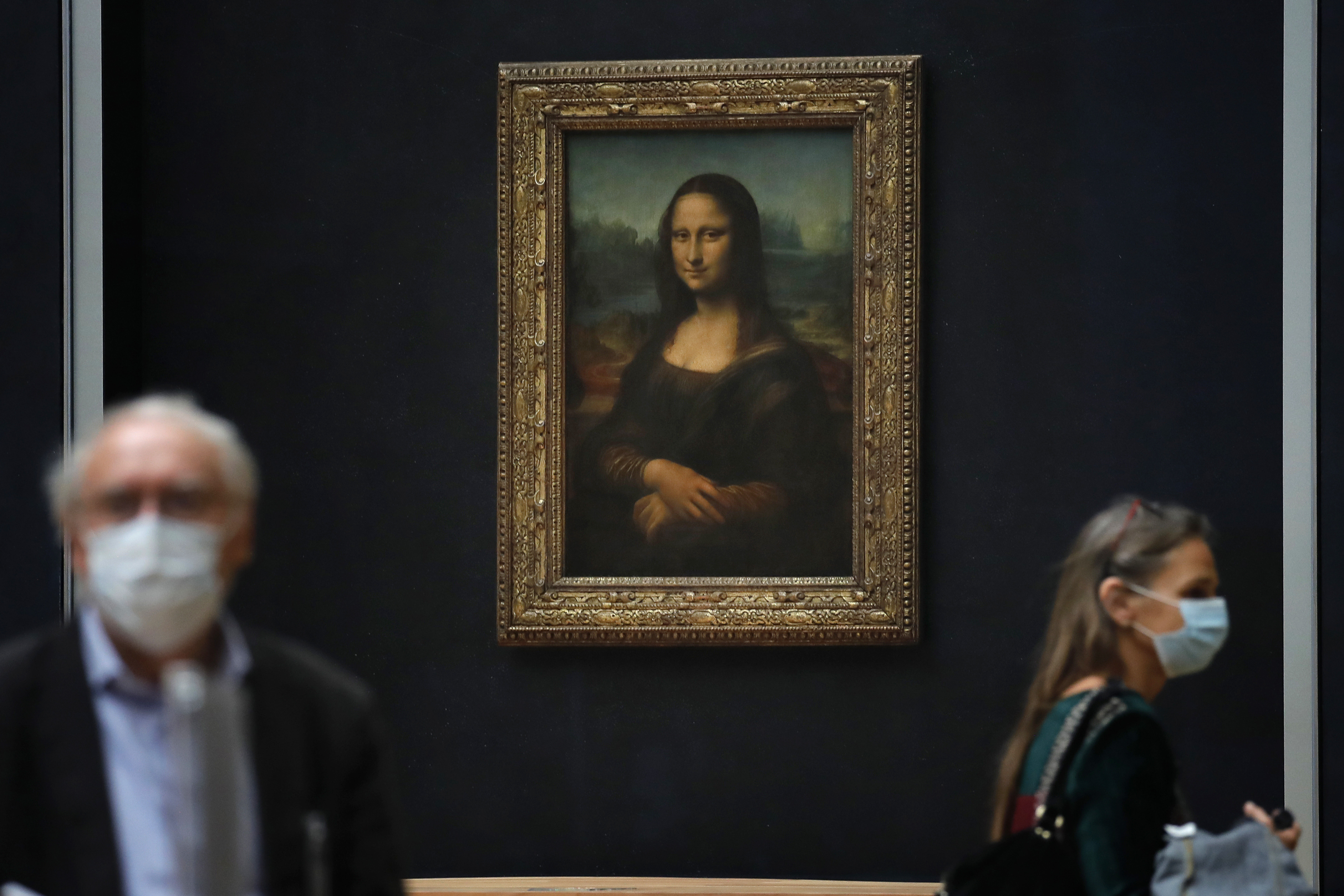 Journalists walk past Leonardo da Vinci's Mona Lisa during a visit of the Louvre museum in Paris .  